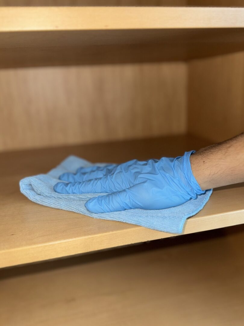 A person wearing blue gloves and cleaning cloth.